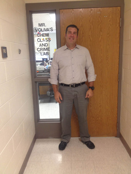 Mr. Voliva smiles for a picture outside his classroom door. 
